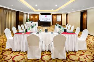 a conference room with tables and chairs and a screen at Millennium Taiba Hotel in Medina