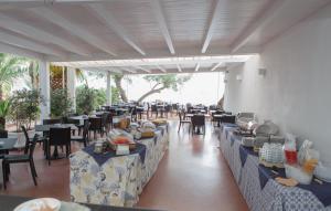a dining room with tables and chairs with food on them at Testa di Monaco Natural Beach in Capo dʼOrlando +57 photos
