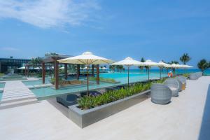 un complexe avec une piscine bordée de parasols, de tables et de chaises dans l'établissement FLC Luxury Resort Quy Nhon, à Quy Nhơn