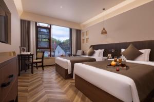 a hotel room with two beds and a table and a desk at Fenghuang Story Hotel in Fenghuang County