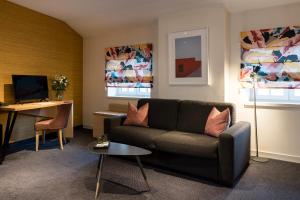 a living room with a couch and a desk at Hôtel Le Griffon d'Or in Bourg-en-Bresse