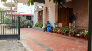 a brick walkway in front of a building with potted plants at Spacious 3-Bedroom Private Villa in Mangalore - Ideal Getaway for Family and Friends in Mangalore