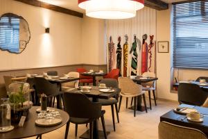 a restaurant with tables and chairs in a room at Hôtel Le Griffon d'Or in Bourg-en-Bresse