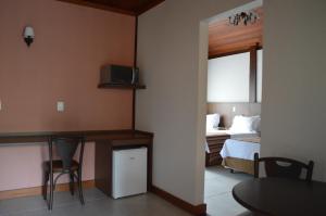 a room with a bedroom with a bed and a table at Pousada Terê Parque in Teresópolis