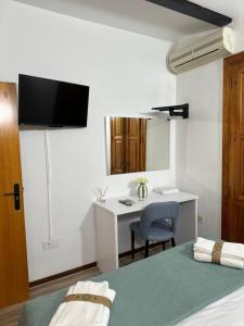 a bedroom with a bed and a desk with a tv on the wall at Mini Peixcateria A in Sagunto