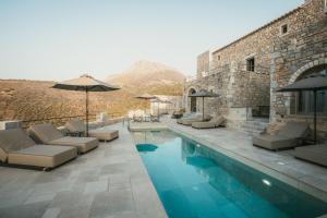 a pool with chairs and umbrellas and a mountain at Nest Limeni in Limeni