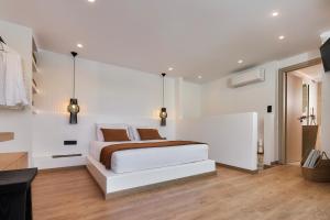 a white bedroom with a bed and a tv at Secret Cave Villa in Matala