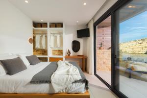 a bedroom with a bed and a large window at Secret Cave Villa in Matala