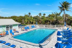 a swimming pool with blue chairs and umbrellas at Seashells #42 in Ybel