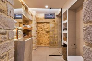 a bathroom with a stone wall at Secret Cave Villa in Matala