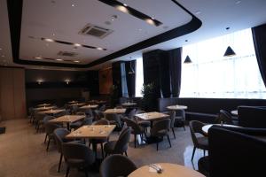 a dining room with tables and chairs and windows at Imperial Riverbank Hotel Kuching in Kuching