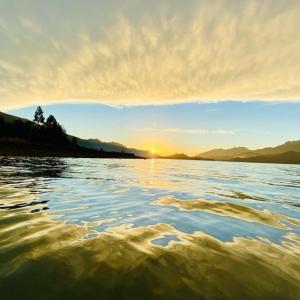 a body of water with the sun setting in the background at Cabaña Estero Mágico in Cochamó +5 photos