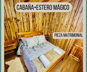a bedroom with a bed in a wooden wall at Cabaña Estero Mágico in Cochamó