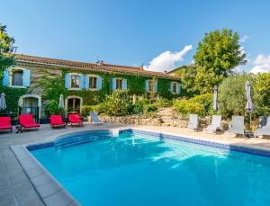 a pool in front of a house with red chairs at Eloi Merle Gîtes in Olonzac