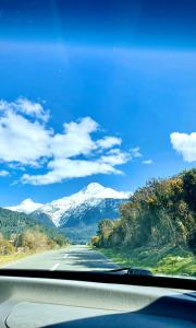 a view of a road with snow capped mountains at Cabaña Estero Mágico in Cochamó