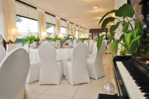 uma sala de jantar com cadeiras brancas e um piano em Pass Hotel em Zebrzydowice