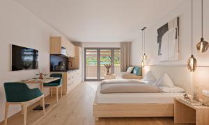 a bedroom with two beds and a table and a kitchen at Das Leonhard - Naturparkhotel am Weissensee in Weissensee