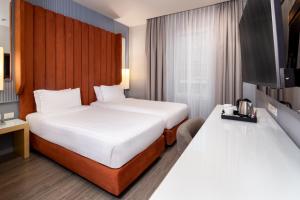 a hotel room with two beds and a tv at Holiday Inn Milan Garibaldi Station by IHG in Milan +130 photos