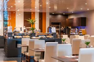 a restaurant with tables and white chairs and a counter at HF Ipanema Porto in Porto