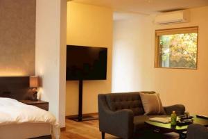 a bedroom with a bed and a couch and a tv at 小宿 和Nagomi in Kobe