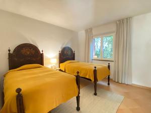 two beds in a room with yellow sheets at Casa Manacá Vilamoura in Quarteira