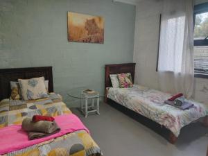 a bedroom with two beds and a glass table at Cocos Island in Bettyʼs Bay +2 photos