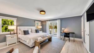 a bedroom with a bed and a desk and windows at Villa Saltwater Haven in East Hampton +42 photos