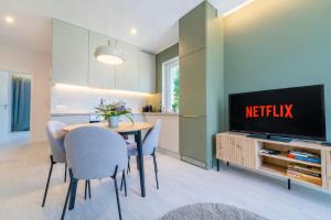 a dining room with a television and a table and chairs at Unique View Apartment - 3pok, 4 łóżka, widok na rzekę, centrum, Netflix, parking, winda in Iława