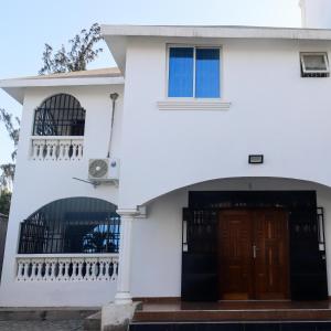 a white house with a door and a balcony at Leah's Luxury Villa in Mombasa
