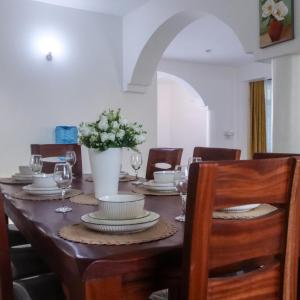 a dining room table with glasses and a vase of flowers at Leah's Luxury Villa in Mombasa