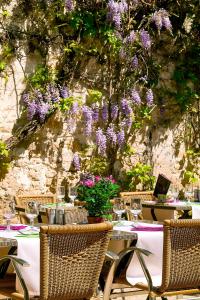 einen Tisch mit Stühlen und einen Tisch mit lila Blumen in der Unterkunft Logis - Hôtel Restaurant l'Ecu de France in Malesherbes
