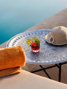 a table with a hat and a drink on it at Palais Dar Souhir in Aït Bou Zguia