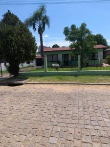 a fence in front of a house with a palm tree at Casa de alquiler M g in Pântano Grande