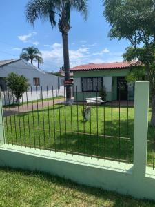 a fence in front of a house with a palm tree at Casa de alquiler M g in Pântano Grande