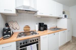 a kitchen with white cabinets and a stove top oven at Liehrstraße 9 by Baltic Home in Heringsdorf +9 photos