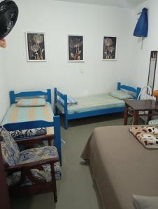 a room with two beds and a chair and a table at Maria Hostel Brasil gru in Guarulhos