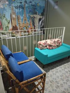 two chairs and a couch in a room with a poster at Maria Hostel Brasil gru in Guarulhos