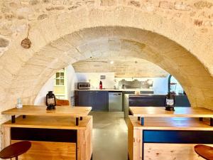 a kitchen with wooden tables and a stone archway at Maison d'hôte Mas de Castille entre Uzès et le pont du Gard in Argilliers
