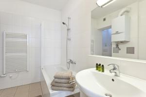 a white bathroom with a sink and a bath tub at HeyMi Apartments Oper in Vienna +96 photos