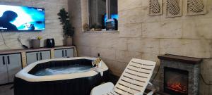 a hot tub in a room with a fireplace and a tv at Спа къща Нико in Elkhovo