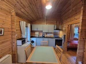 a kitchen in a log cabin with a table and chairs at Eas Lodge in Tobermory +3 photos