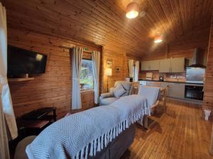 a living room with a bed and a kitchen at Eas Lodge in Tobermory