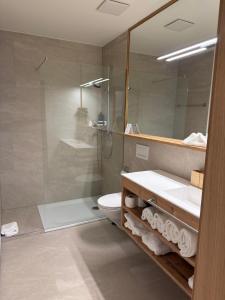 ein Badezimmer mit Dusche, Waschbecken und Toilette in der Unterkunft Gemmi Hotel & Spa in Kandersteg + 38 Fotos