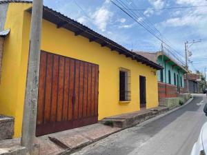 a yellow building with a wooden door on a street at Modern colonial house in Apastepeque
