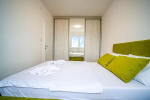 a bedroom with a large white bed with green pillows at Renome apartmani in Banja Koviljača