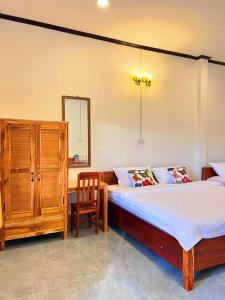 a bedroom with two beds and a cabinet and a chair at phoulisack2 guesthouse in Nongkhiaw