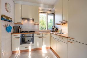 a kitchen with white cabinets and a window at BlauweBoshuis in Koekange +20 photos