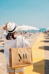 a woman carrying a tote bag on the beach at J44 Lifestyle Hotel in Lido di Jesolo
