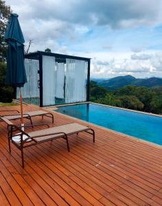 a deck with an umbrella and a bench next to a pool at Sítio Turisfri in Nova Friburgo