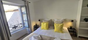 a bedroom with a bed with yellow pillows and a window at Le Patio de l'Isle 2nd Duplex in Périgueux